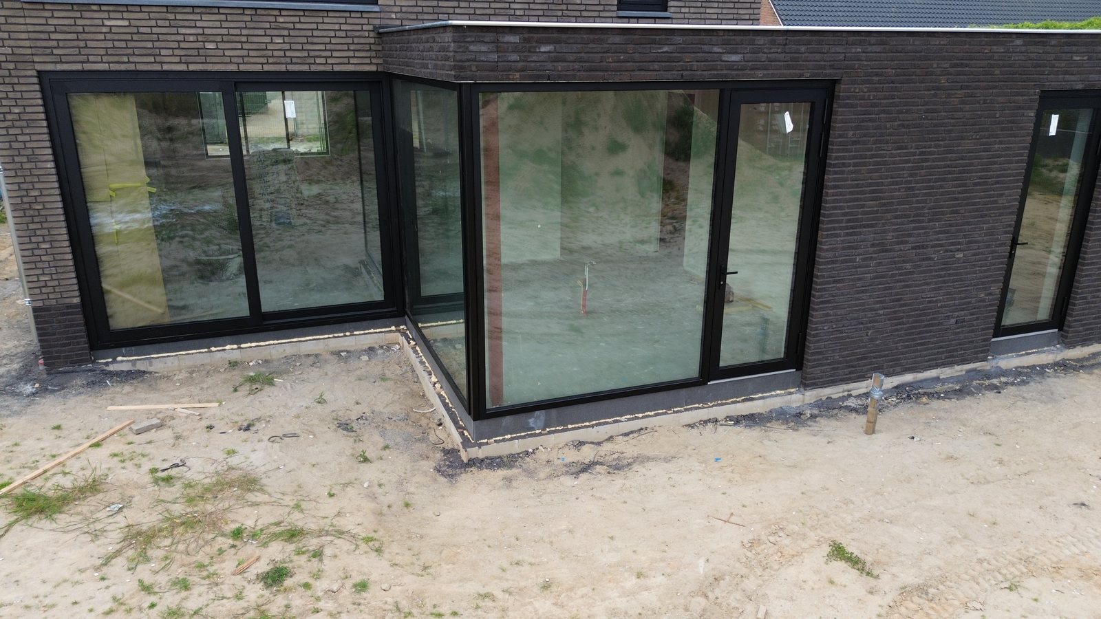 De aanbouw met plat dak en een brede pui
